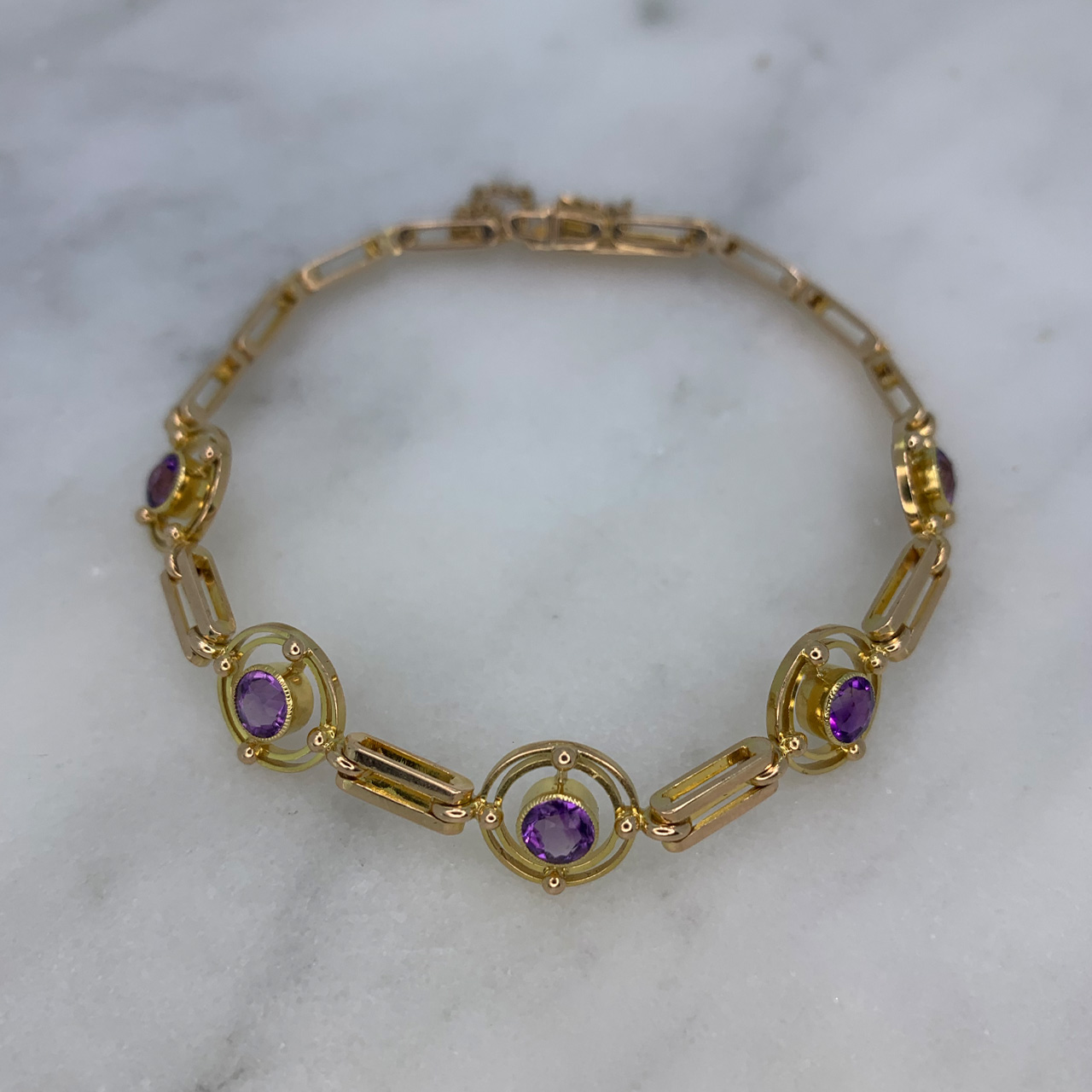 Exquisite Edwardian Gemetric Amethyst Bracelet in 15ct stamped buttery yellow Gold. The bracelet has five 4.3 diameter Cabochon amethysts in rub over setting, surrounded by a cicular design circa the Edwardian era. The gate link chain fastens with a snap clasp and box and measures 182mm, with a 60mm safety chain. Immaculate condition and craftsmanship. 