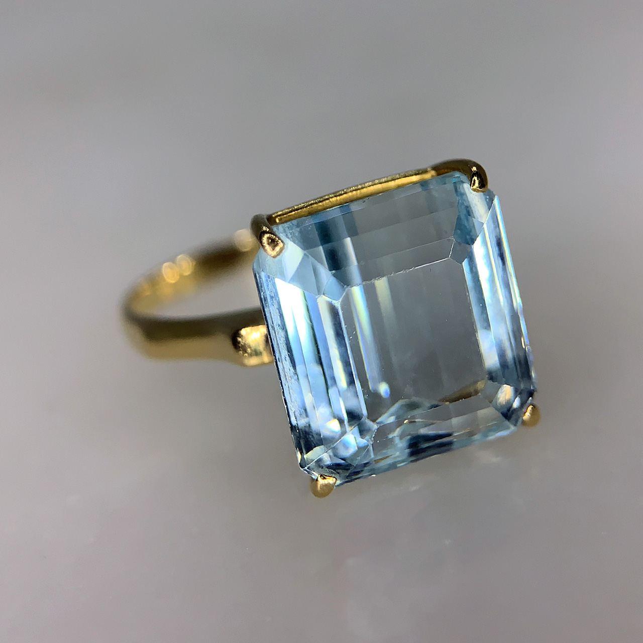 Vintage Solitaire Aquamarine Cocktail Ring. The emerald cut, crystal clear 5.5ct aquamarine jewel is set within a 18ct yellow gold basket.