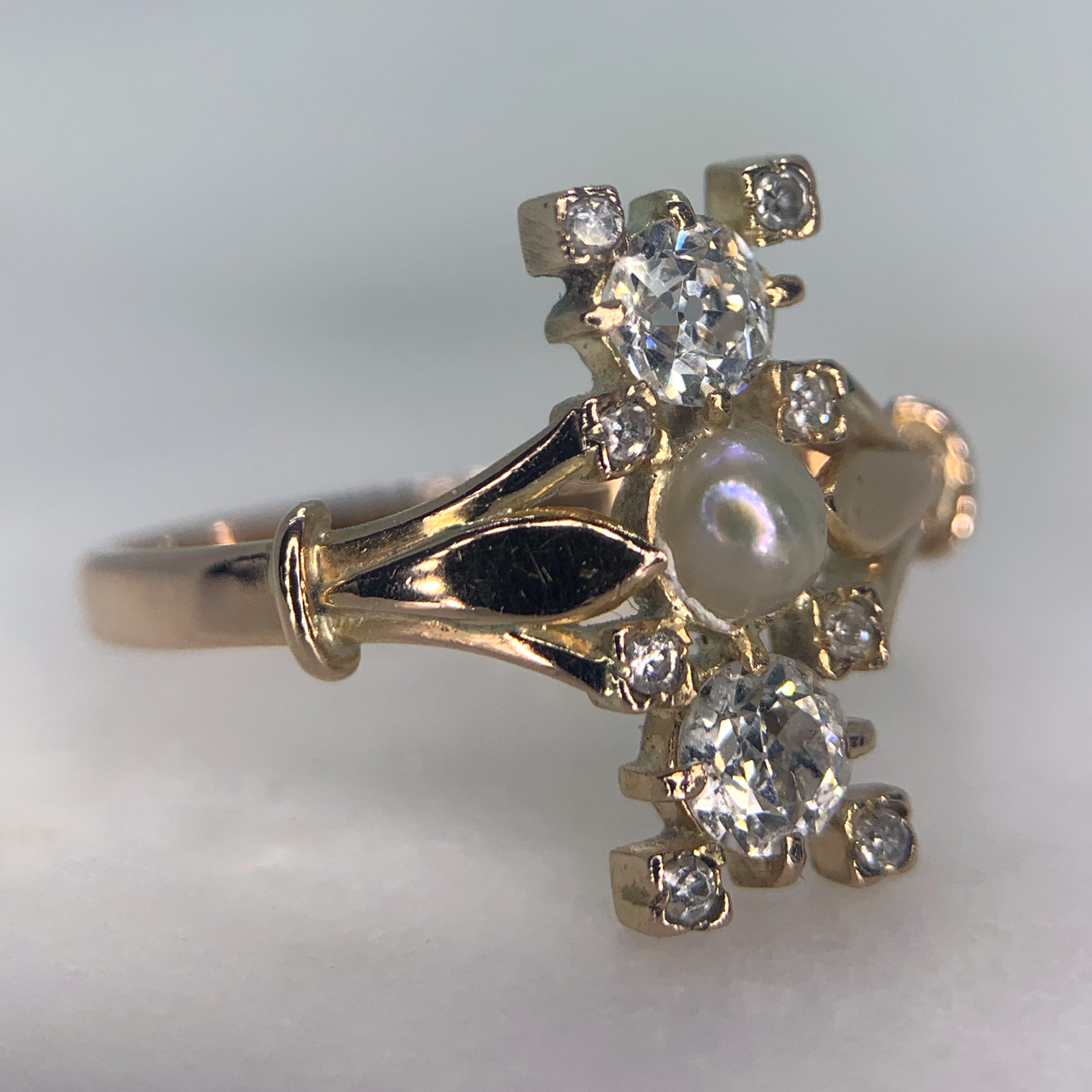 Stunning Diamond and Pearl Upfinger Ring. The ring  is decorated with a singular half pearl of 4mm x 3.5mm approximately and two diamonds. Framing the three principle stones is eight micro-diamonds, all the diamonds are claw set. The head of the ring measures approximately 15.25mm x 6.75mm with a split shoulder polished shank. A beautiful and elegant example of an antique ring in excellent condition.