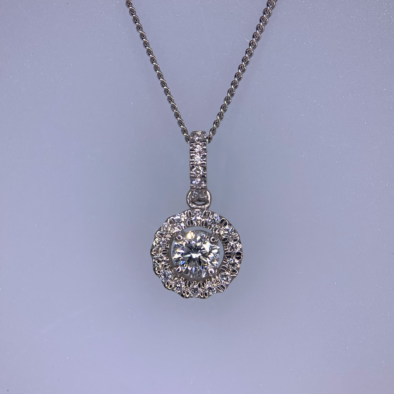 Diamond Cluster Pendant in 950 Platinum. The pendant holds 0.41 carat of diamond, with 14 smaller surrounding diamonds, the pendant measures approximately 9mm x 9mm. The pendant loop is 6mm and holds six smaller diamonds. All stones are claw set. 