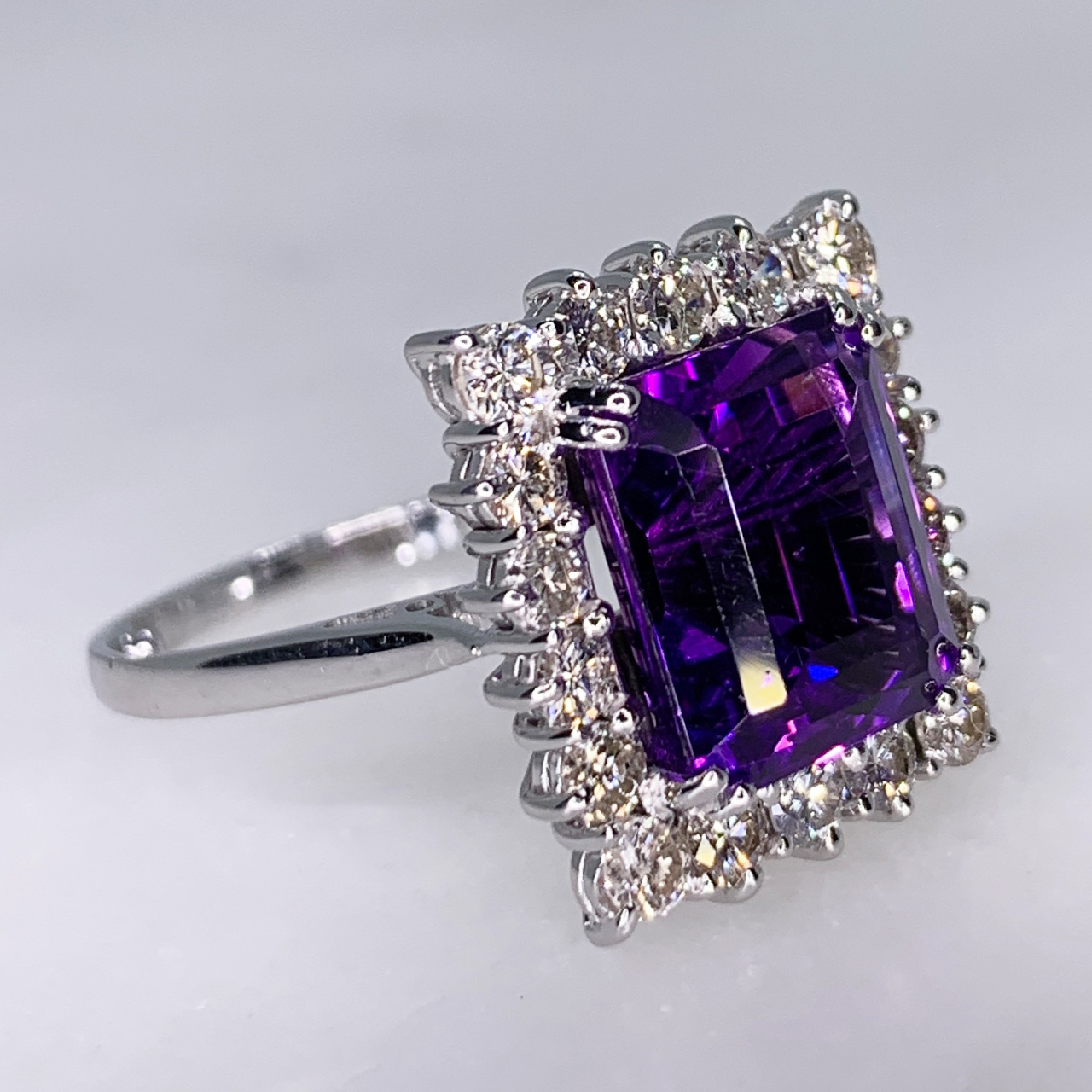 Vintage Amethyst and Diamond Rectangular Cluster set in Platinum. This exquisite emerald cut multi-tone Amethyst measures approximately 9mm x 11mm with a total weight of 7 carats. The central Amethyst is surrounded by 18 brilliant cut white diamonds total diamond weight 1 carat. All stones are claw set. The ring has a tiffany shank with size adjustment on the inside in perfect condition.
