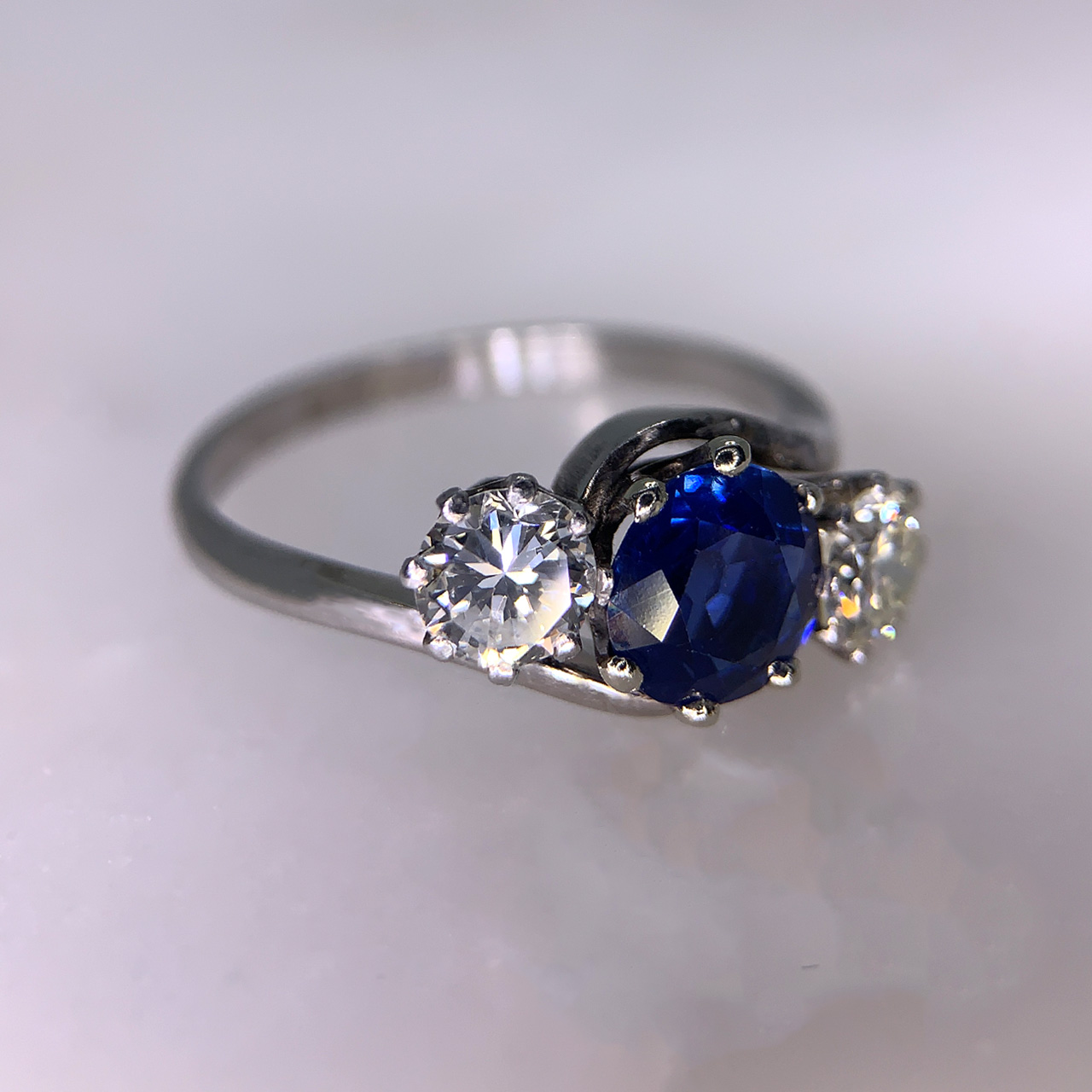 1930's Diamond and Sapphire Twist Trilogy Ring in hallmarked Platinum. This exquisite multi-tone Sapphire, 1.5 carats diamond weight is enclosed by two brilliant cut 1/2 carat diamonds. All stones are claw set. The head of the ring is approximately 17mm x 8.5mm and sits within a twist shank in the most perfect condition.